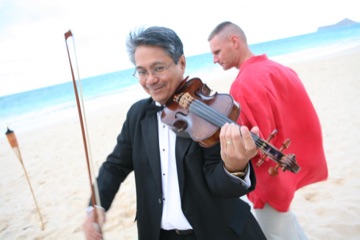 Smiling violinist in a tuxedo playing on the beach in Hawaii